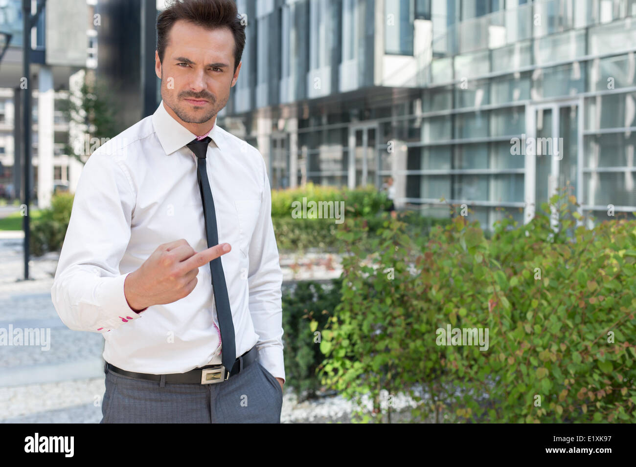 Portrait de angry businessman showing doigt moyen outside office building Banque D'Images
