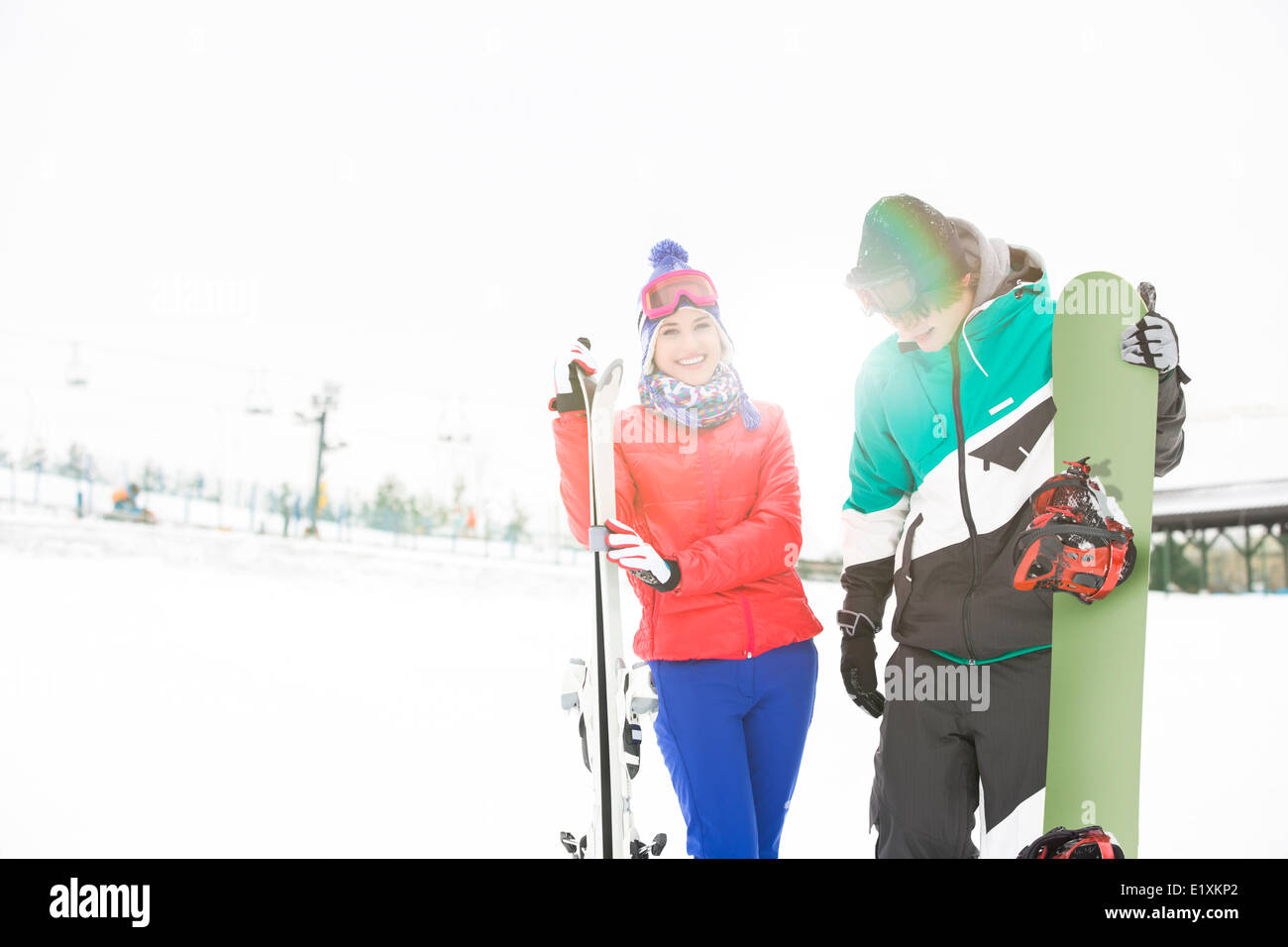 Happy young couple with snowboard et skis dans la neige Banque D'Images