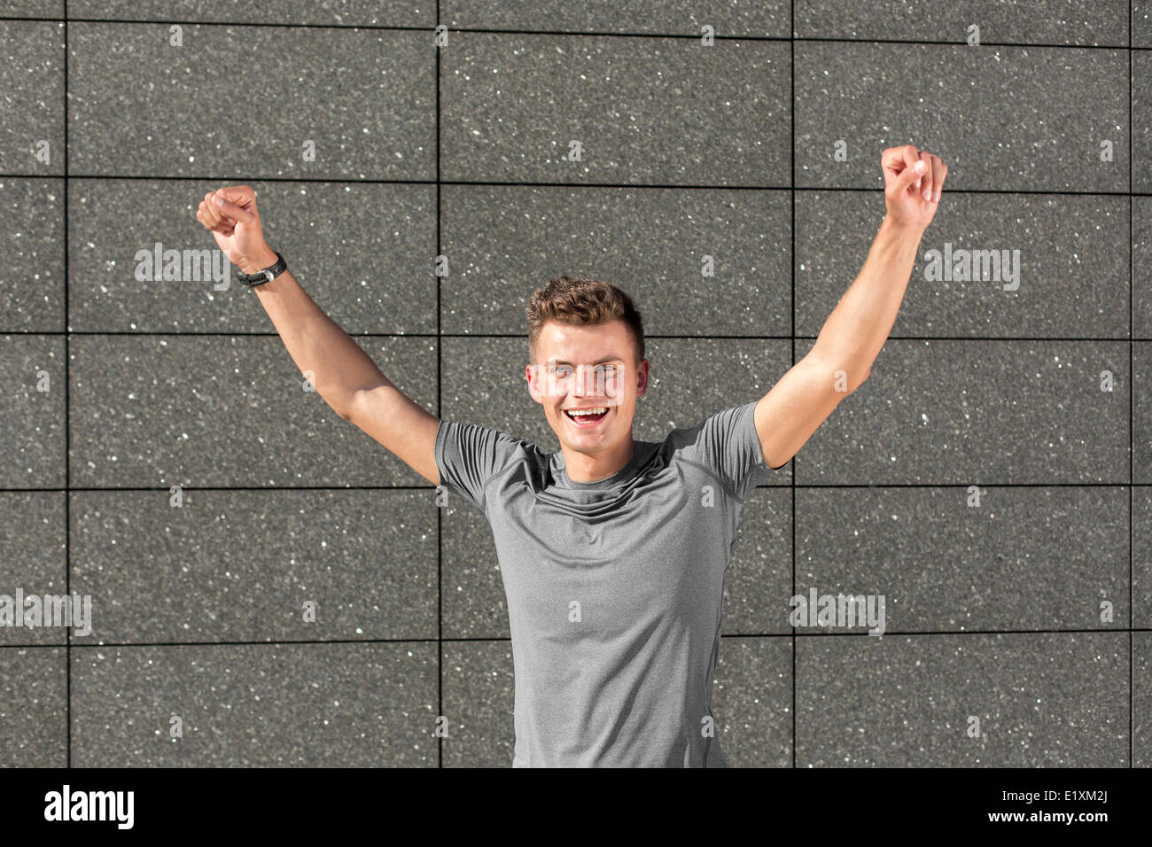 Portrait d'homme jogger avec poing serré contre le mur carrelé Banque D'Images