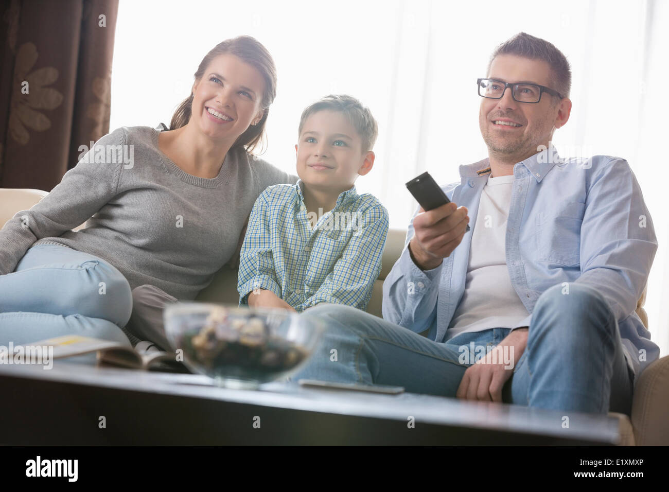 Garçon regardant la TV avec les parents dans la salle de séjour Banque D'Images