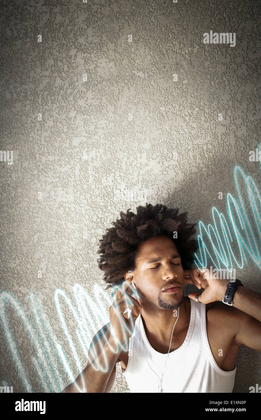 Jeune homme écoute détendue de la musique tout en se penchant sur le mur Banque D'Images
