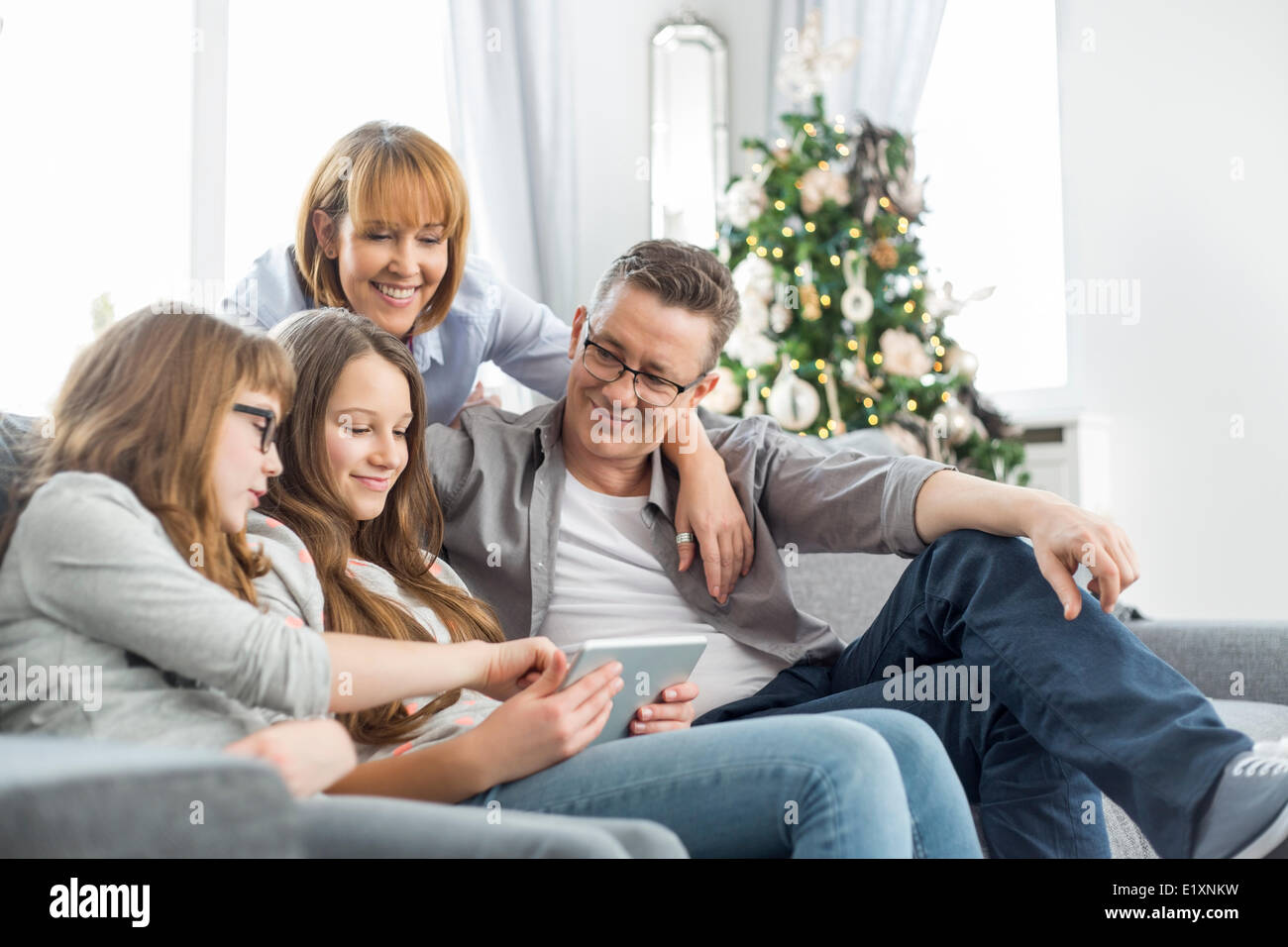 À l'aide de la famille tablet PC sur canapé avec arbre de Noël en arrière-plan Banque D'Images