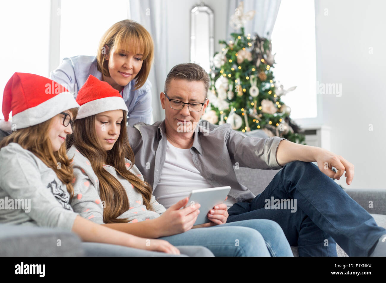Famille de quatre using digital tablet at home during Christmas Banque D'Images