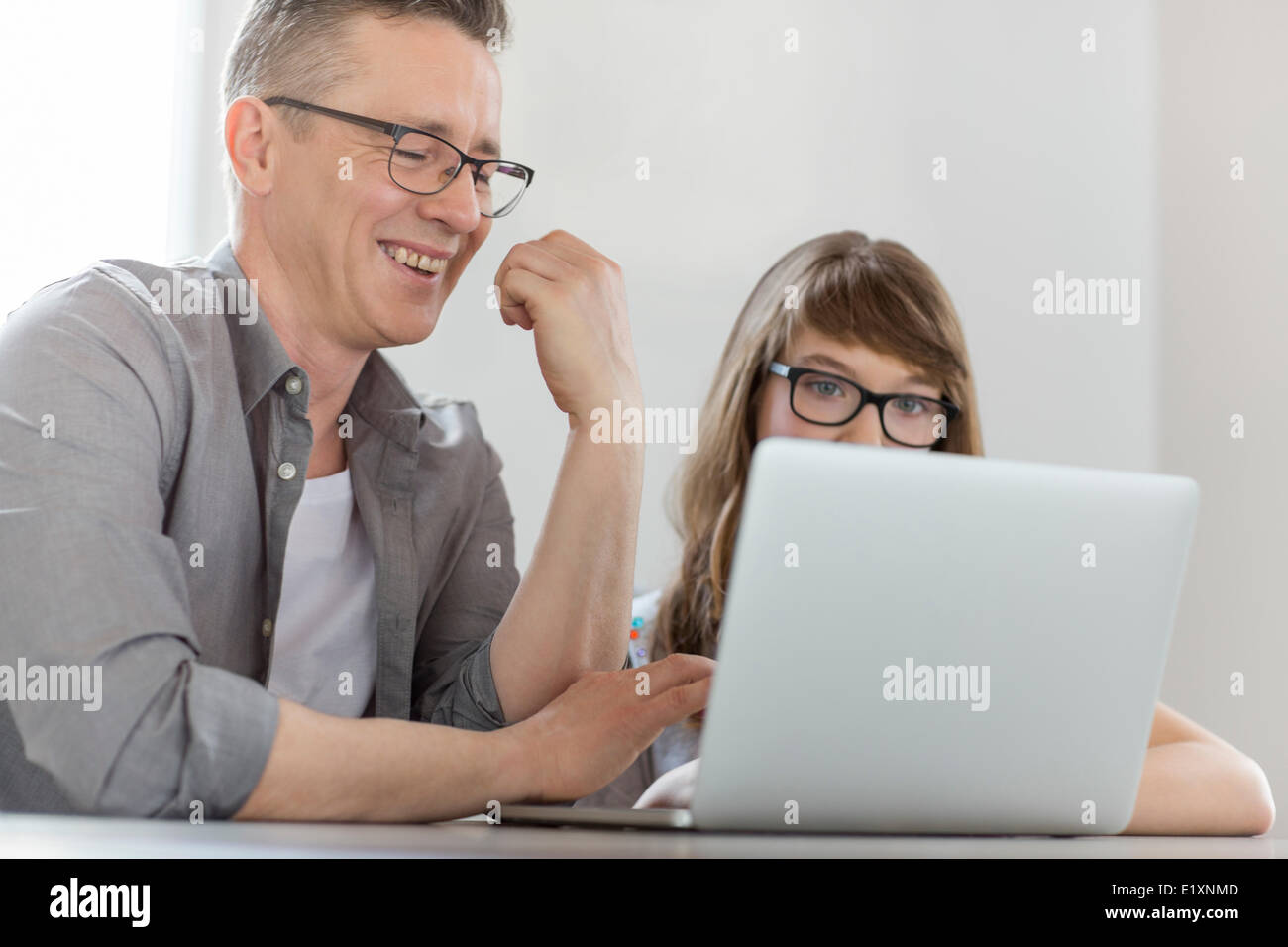 Homme heureux à l'aide d'un ordinateur portable avec sa fille à la maison Banque D'Images