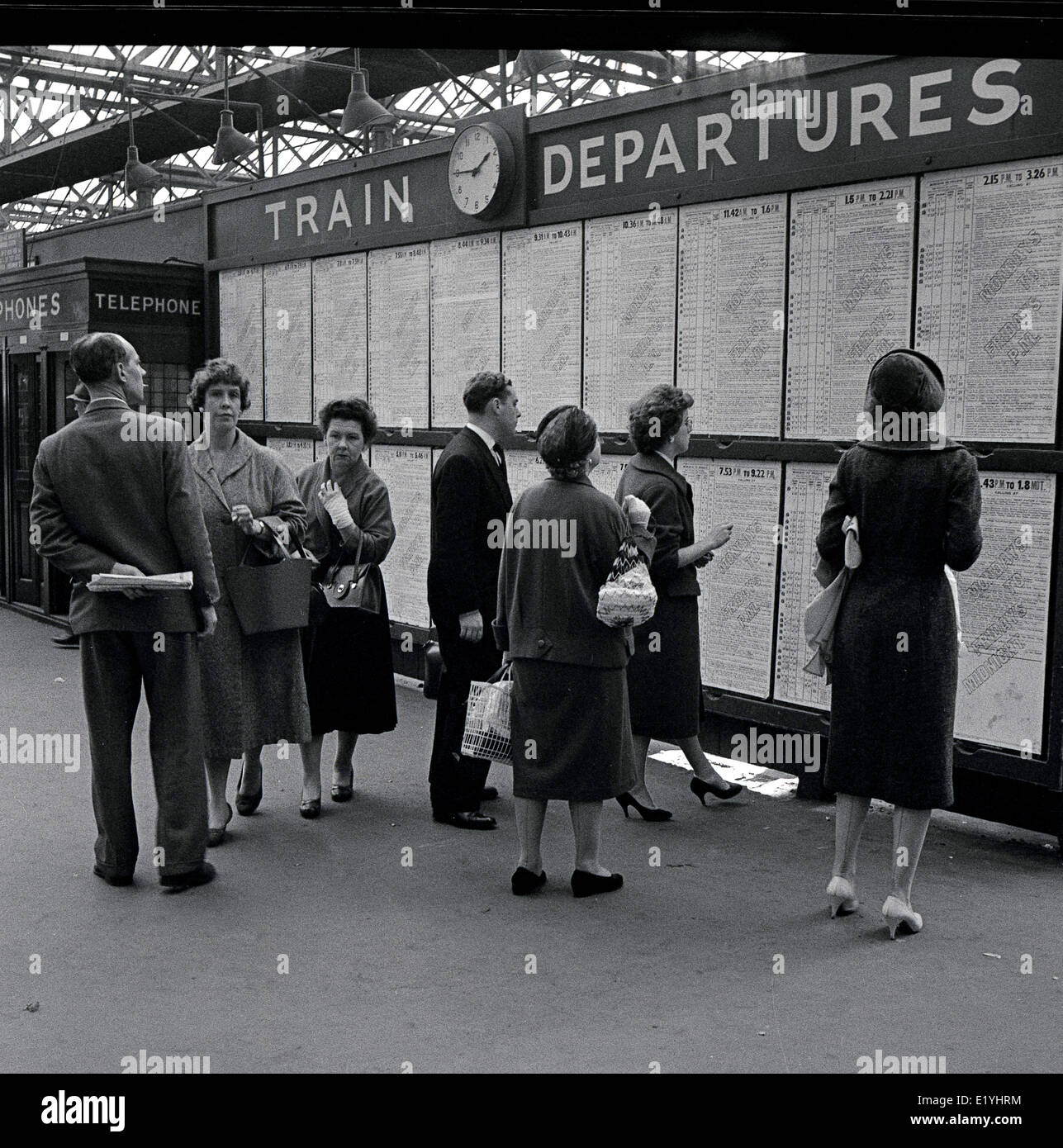 Historique des années 1950, bien habillés des profils des voyageurs à la recherche à la Commission dans le hall des départs à la gare de Waterloo, Lambeth, Londres. Banque D'Images