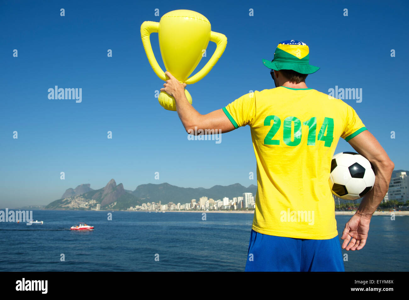 Footballeur en 2014 Chemise en couleurs Brésil équipe célébrer holding trophy et Rio Ipanema Beach soccer ball Banque D'Images