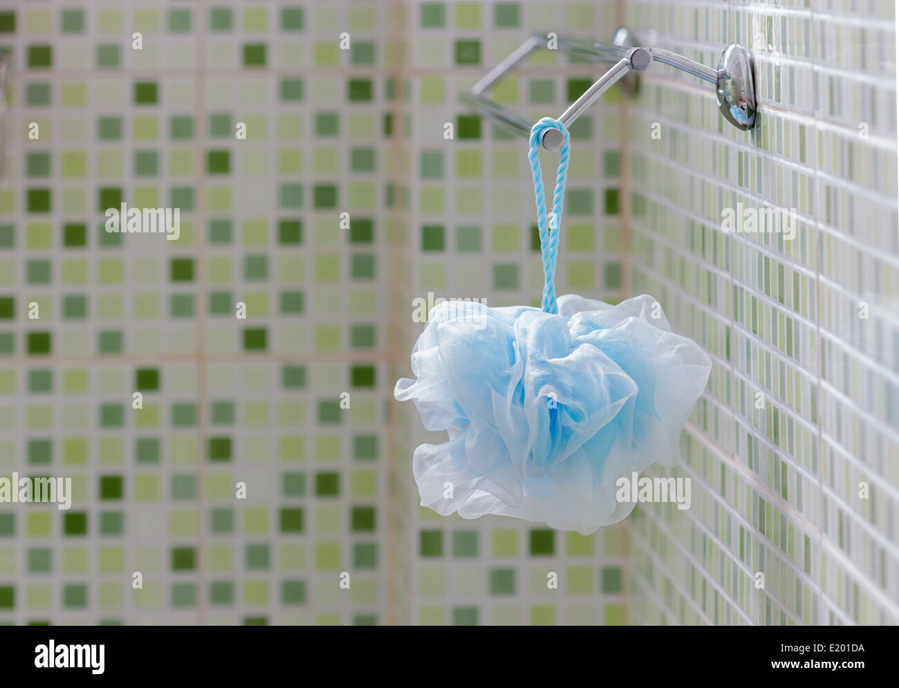 Scrub fibre bleue suspendue sur le rail dans la salle de bains avec carreaux verts. Banque D'Images