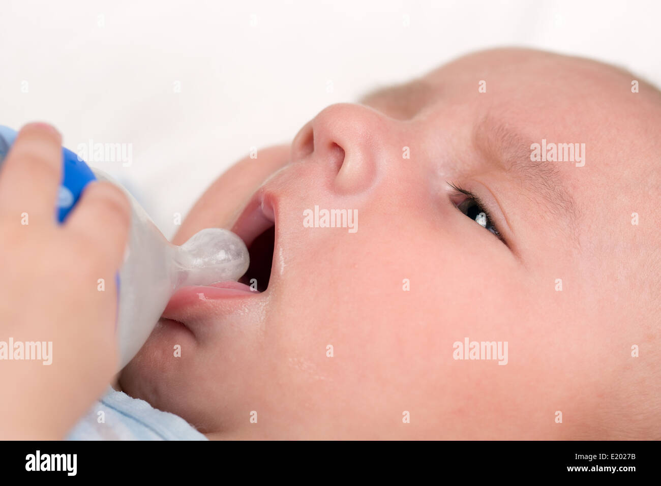 Un petit bébé ouvre sa bouche et boire du lait d'une bouteille Banque D'Images