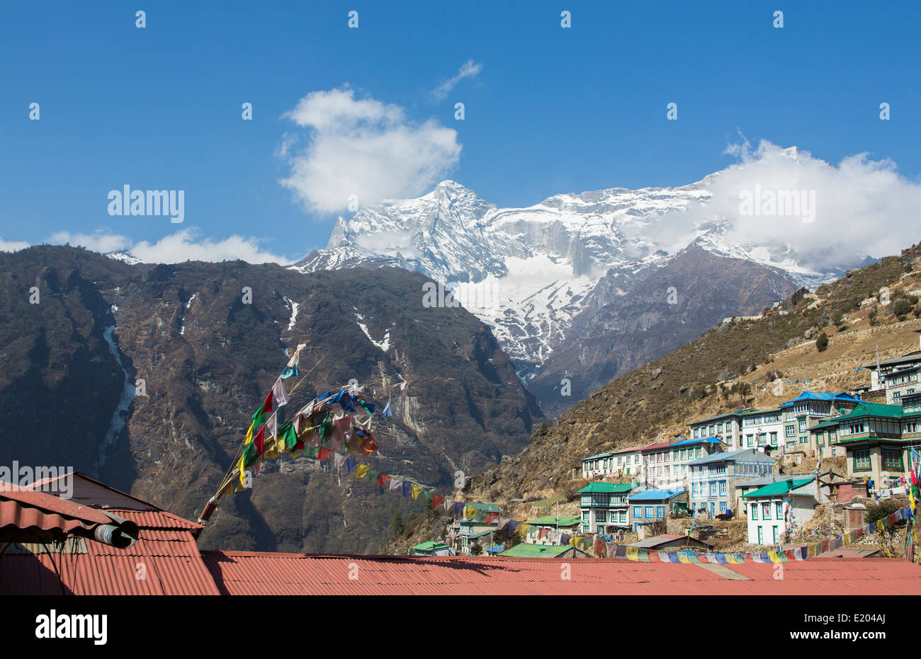 Le Népal Namche Bazarre. Les drapeaux de prières sur les bâtiments avec montagnes en arrière-plan, le Mt Everest à distance Banque D'Images