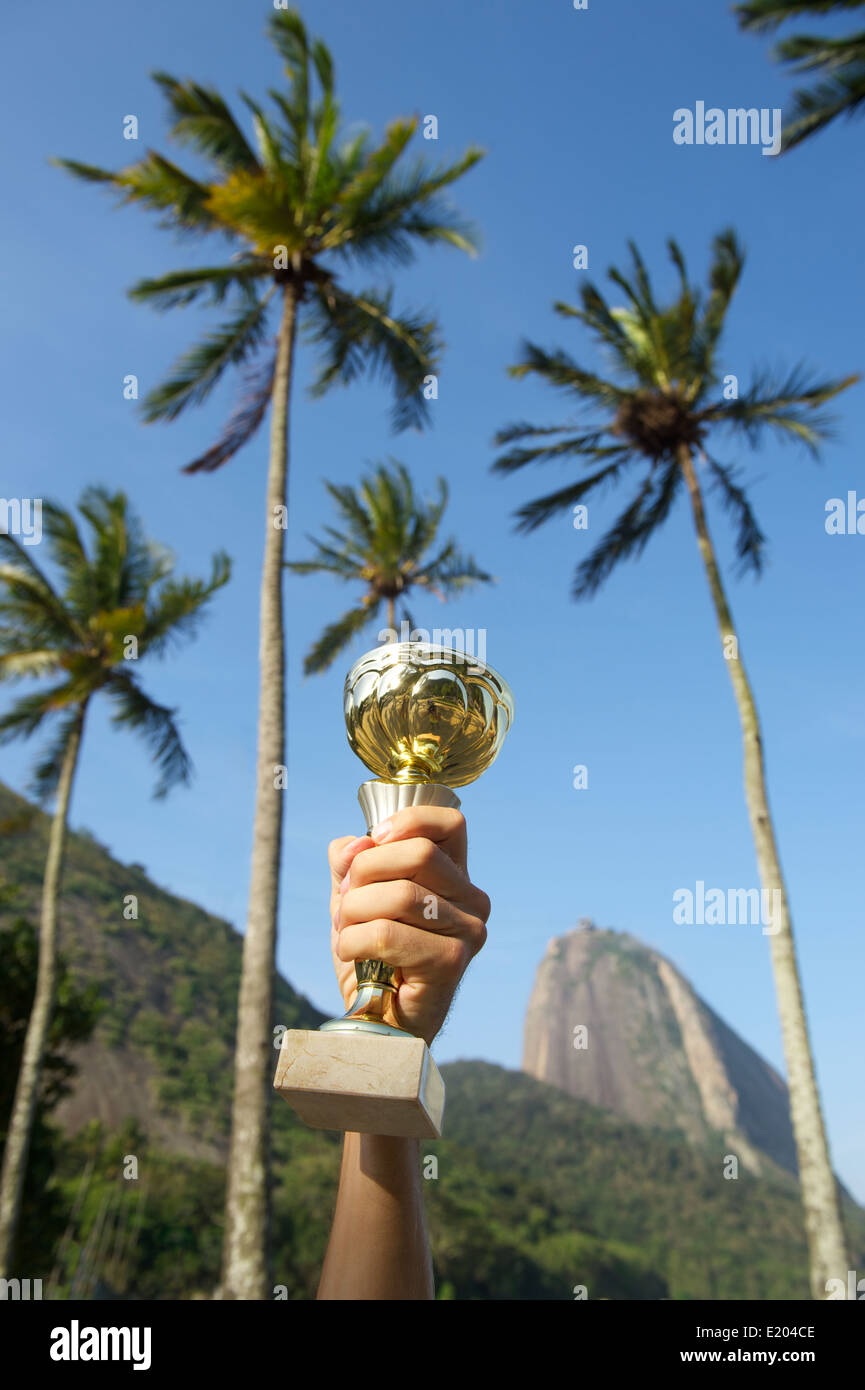 Hand holding inflatable trophy au-dessus de palm tree skyline at Mont Sugarloaf Rio de Janeiro Brésil Banque D'Images