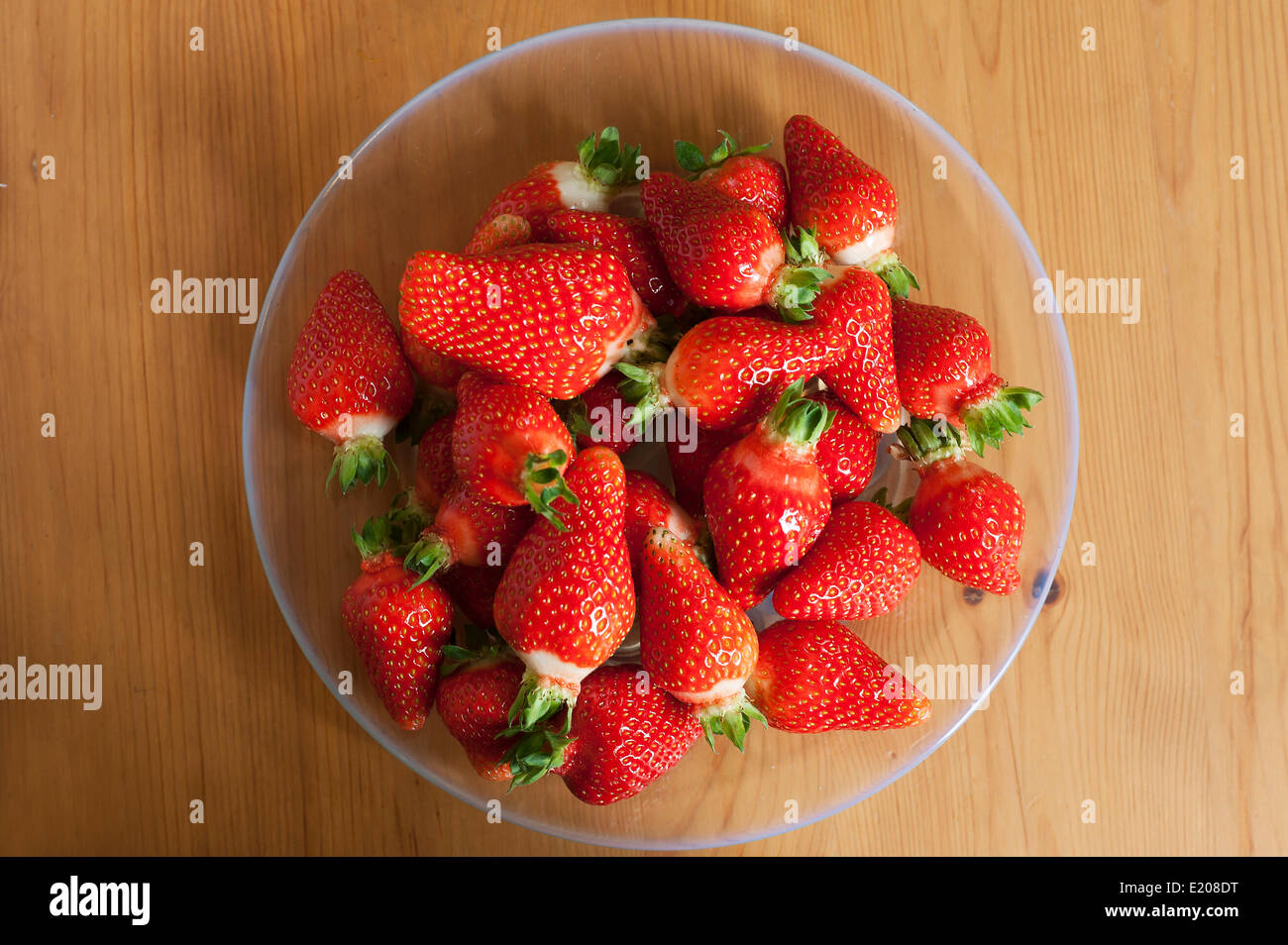 Fraises fraîches sur une plaque de verre sur fond de bois Banque D'Images