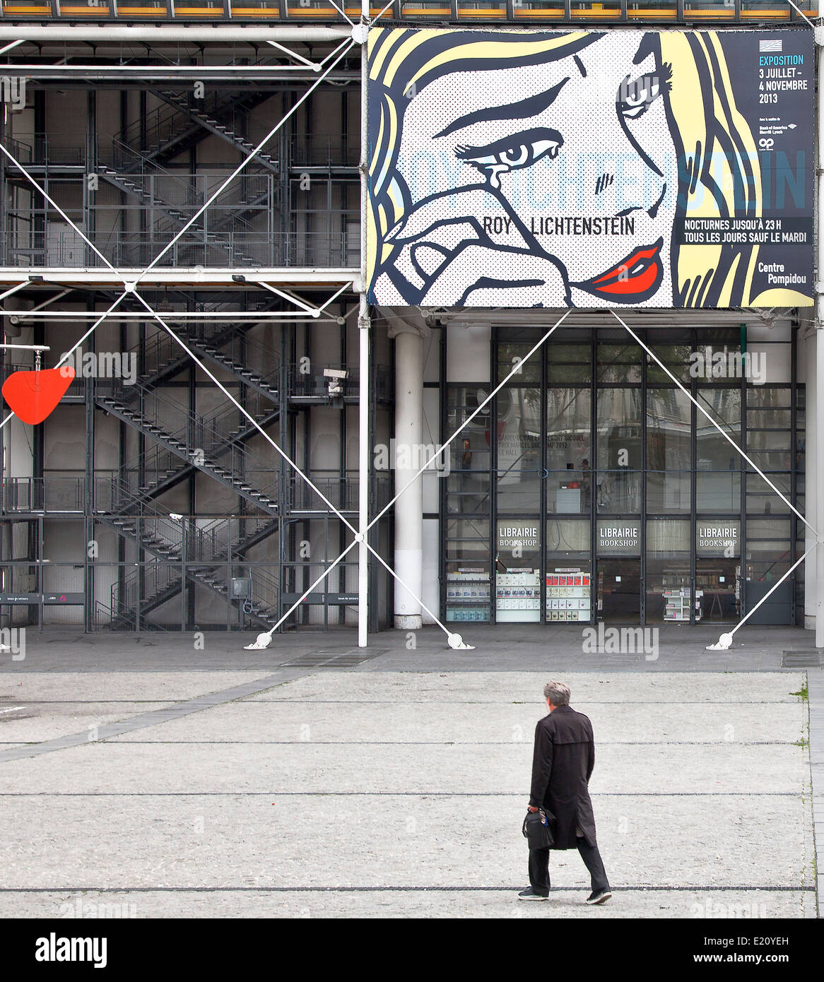 L'homme en manteau noir marchant sur la place Pompidou Paris à bâtir avec tête de la femme aux cheveux blonds et aux lèvres rouge Banque D'Images