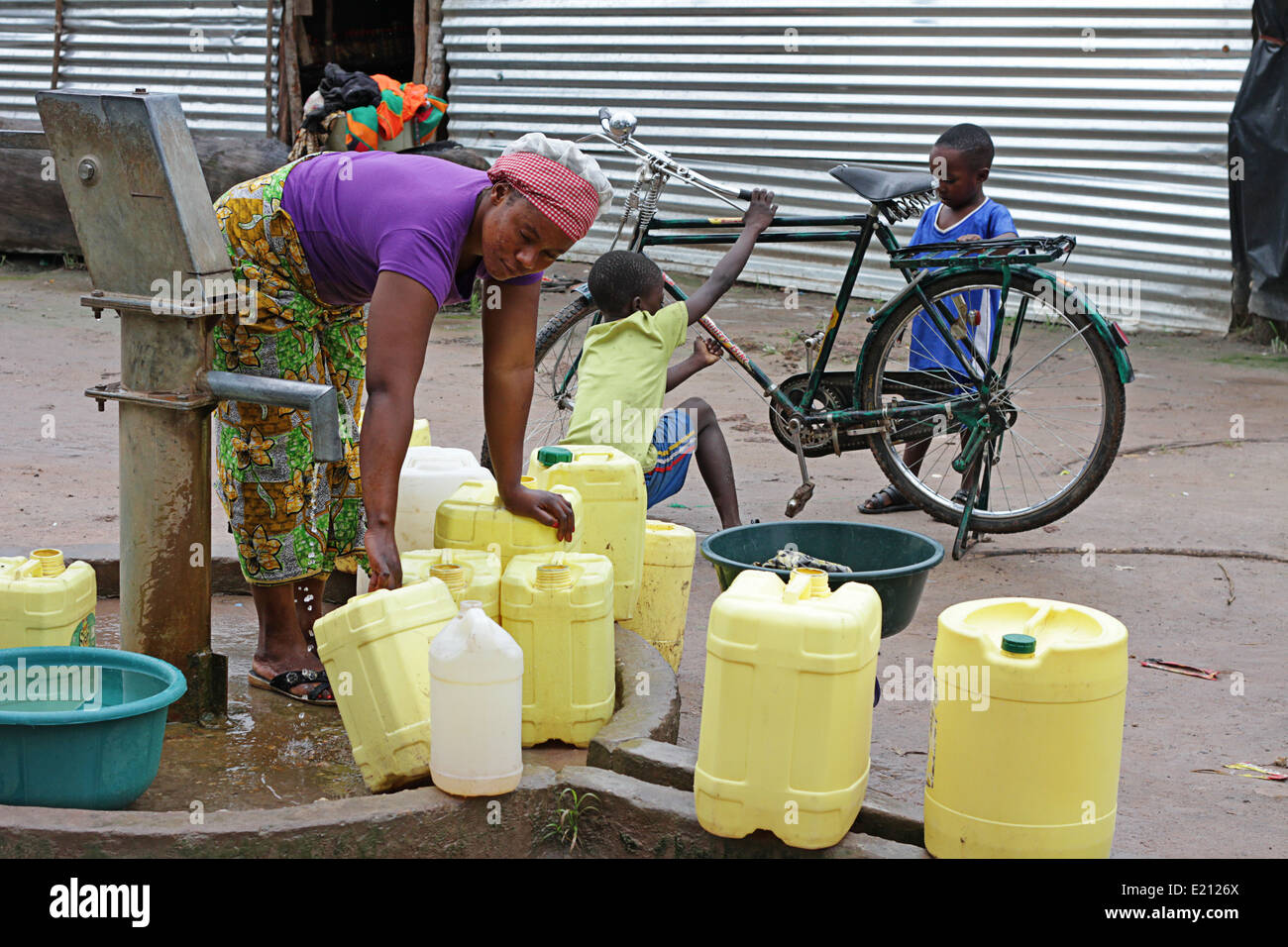 Une femme zambienne des contenants en plastique de remplissage avec de l'eau pour le lavage et la consommation Banque D'Images