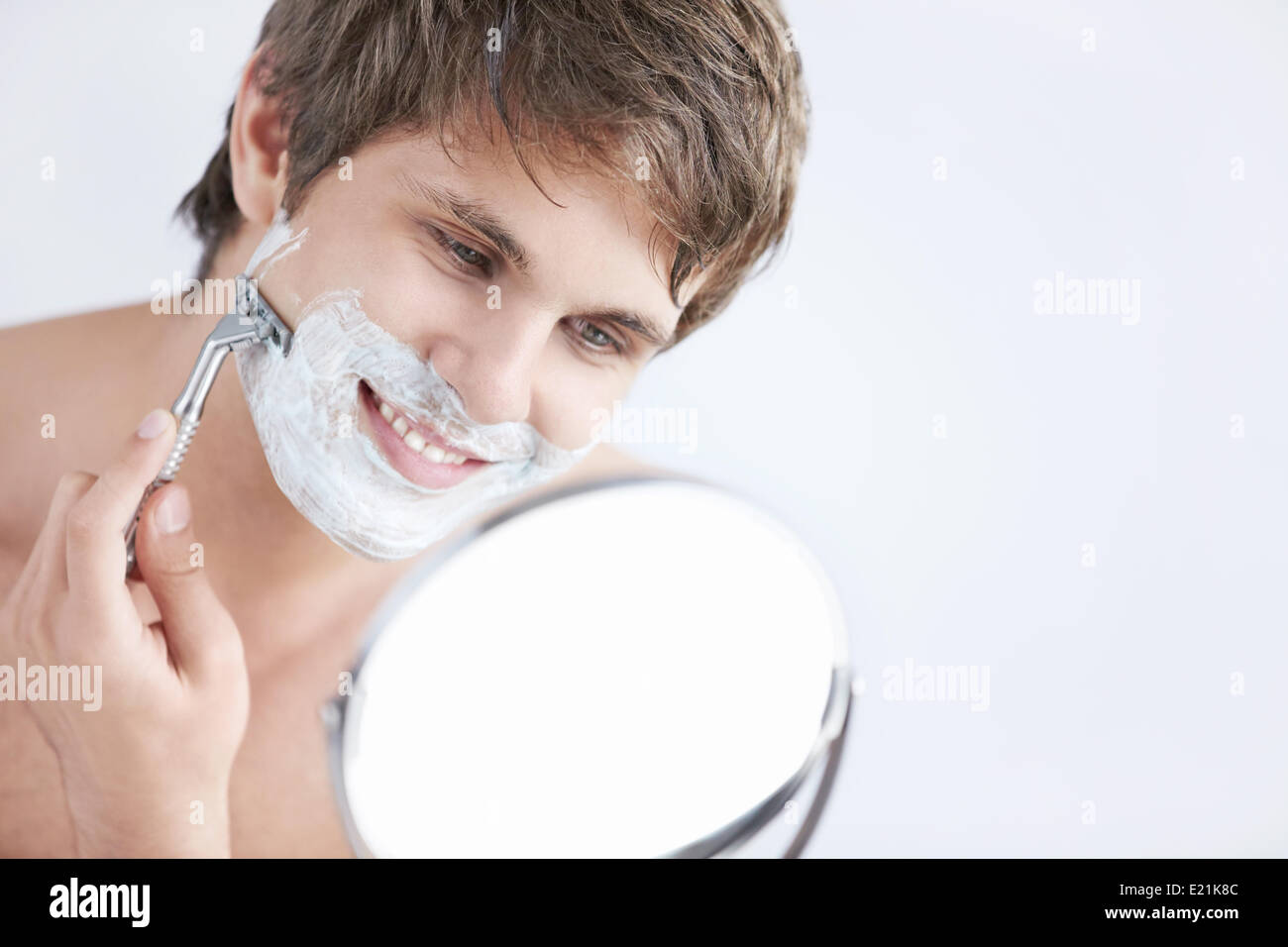 Jeune homme attrayant se rase dans le miroir, se raser gay dans le peignoir  dans la salle de bains Photo Stock - Alamy