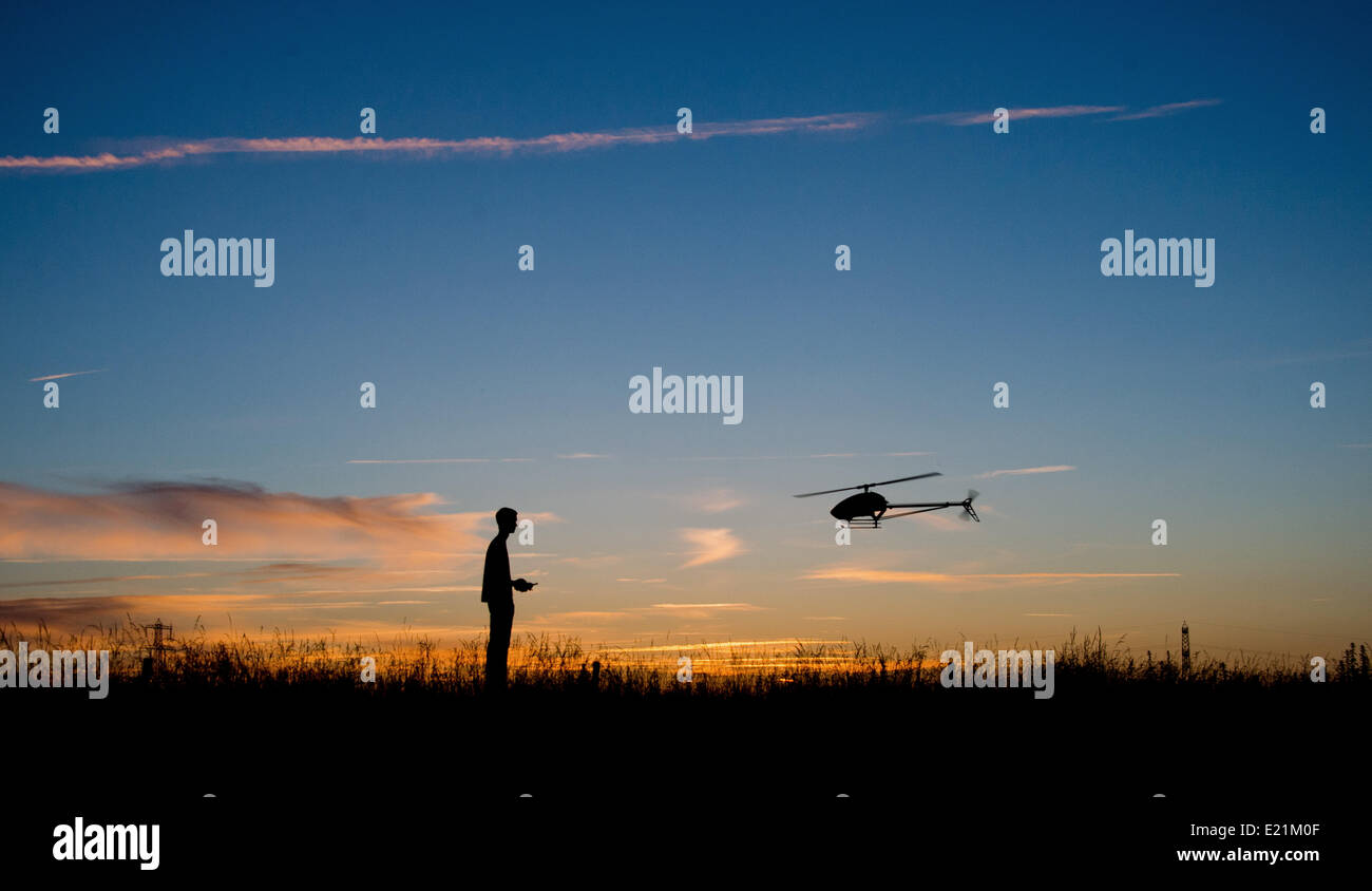 Gleidingen, Hannover, Allemagne. 12 Juin, 2014. Marcel Permin, 20 ans, commande un modèle hélicoptère pendant un coucher de soleil sur un champ à Gleidingen, Hanovre, Allemagne, 12 juin 2014. Le petit hélicoptère avec jusqu'à 1,50 mètres Envergure est contrôlé à distance par radio. Des pointes de vitesse de plus de 200 kilomètres par heure, le modèle flyer diriger l'hélicoptère via secure prés et champs de maïs. Photo : JULIAN STRATENSCHULTE/dpa/Alamy Live News Banque D'Images