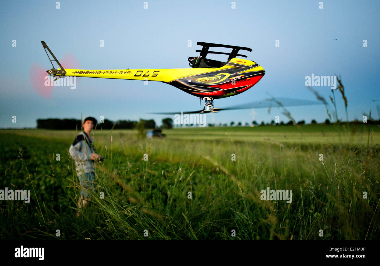 Gleidingen, Hannover, Allemagne. 12 Juin, 2014. Yanik Wolter, 16 ans, commande un modèle hélicoptère pendant un coucher de soleil sur un champ à Gleidingen, Hanovre, Allemagne, 12 juin 2014. Le petit hélicoptère avec jusqu'à 1,50 mètres Envergure est contrôlé à distance par radio. Des pointes de vitesse de plus de 200 kilomètres par heure, le modèle flyer diriger l'hélicoptère via secure prés et champs de maïs. Photo : JULIAN STRATENSCHULTE/dpa/Alamy Live News Banque D'Images