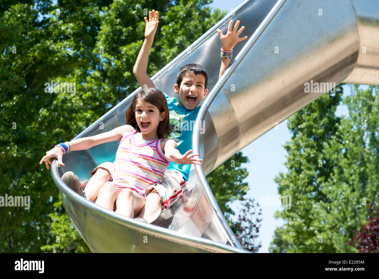 Les jeunes enfants équitation le curseur dans le parc Banque D'Images