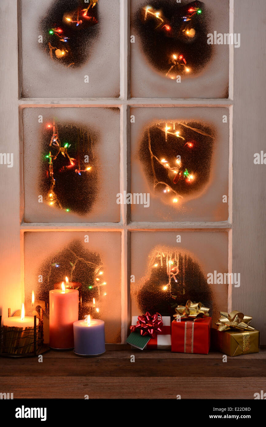 Une fenêtre avec des couverts de givre. Les lumières de Noël brillent à l'extérieur de la fenêtre tandis que l'intérieur d'une table rustique a présente Banque D'Images