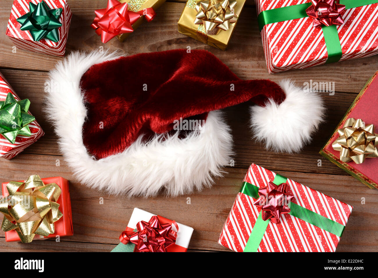 Vue de dessus d'un chapeau de Père Noël entouré par des cadeaux de Noël sur un plancher en bois rustique. Format horizontal en remplissant le cadre. Banque D'Images