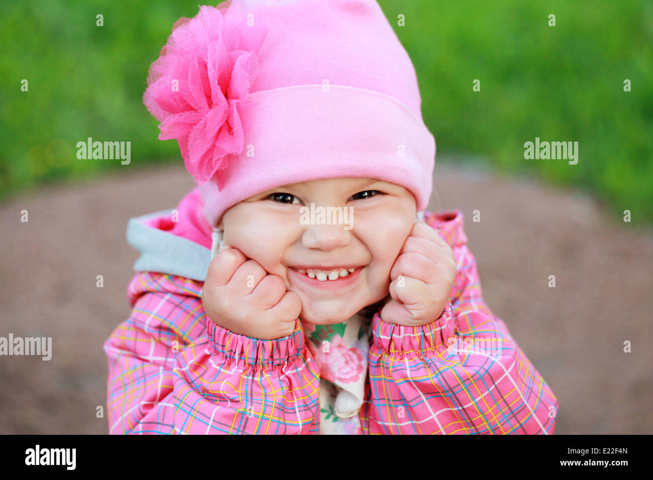 Funny rire Caucasian baby girl in pink, portrait en extérieur Banque D'Images