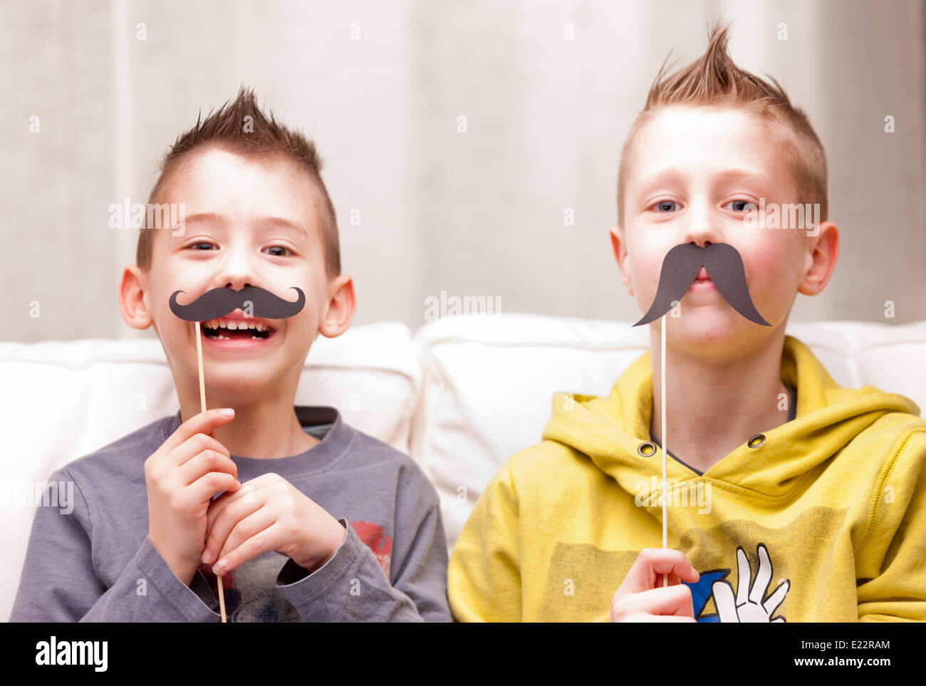 Deux enfants faire des grimaces avec de fausses moustaches Banque D'Images