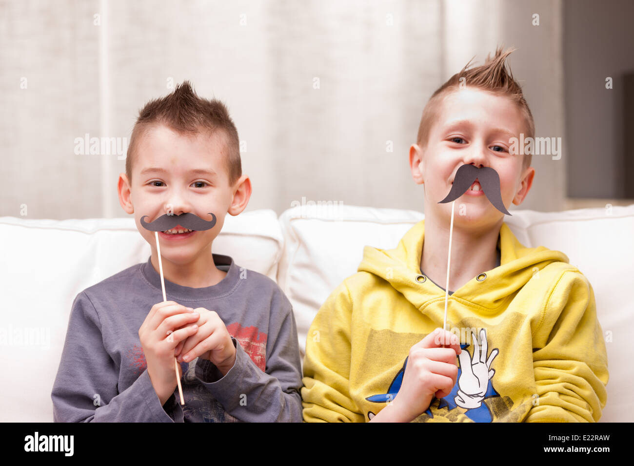 Deux enfants faire des grimaces avec de fausses moustaches Banque D'Images