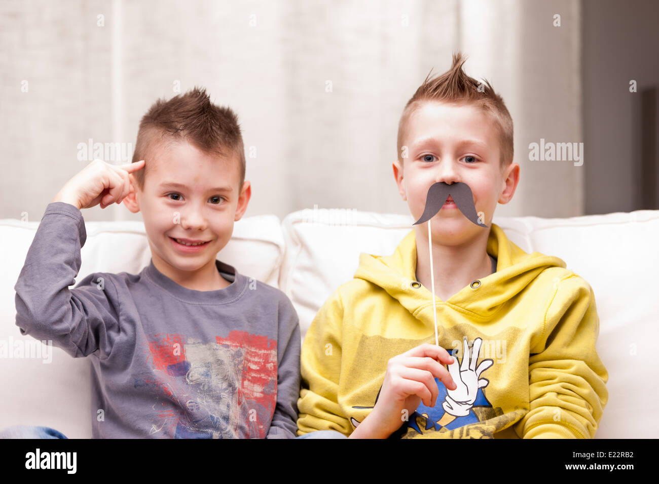 Deux enfants faire des grimaces avec de fausses moustaches Banque D'Images