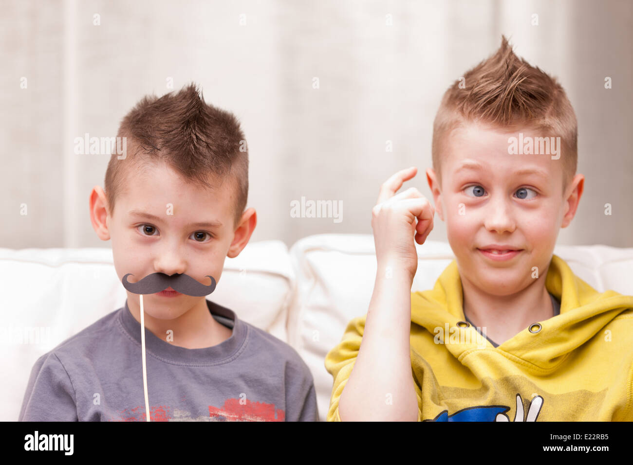 Deux enfants faire des grimaces avec de fausses moustaches Banque D'Images