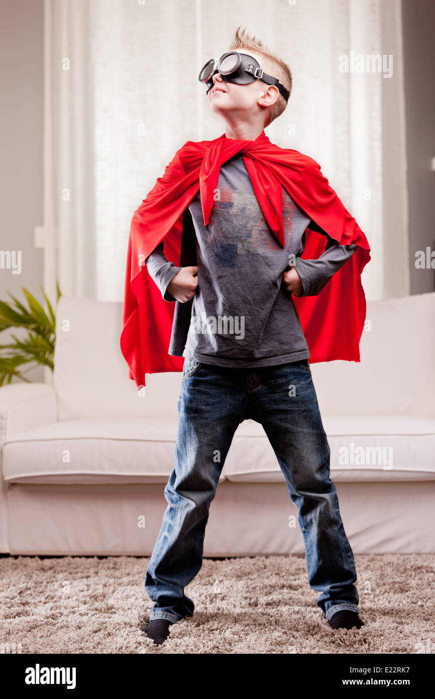 Un petit enfant jouant comme un manteau rouge super-héros grave Banque D'Images