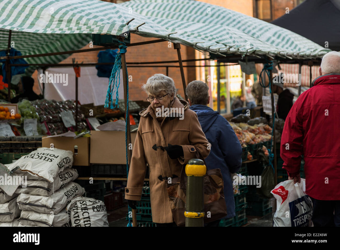 Journée froide sur le marché à Merthyr Tydfil shoppers que sélectionner les fruits et légumes d'étals de marché. Banque D'Images