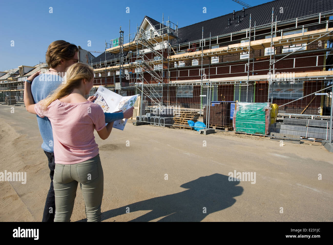 Jeune couple avec blueprint est à la recherche de maisons nouvellement construites on construction site Banque D'Images