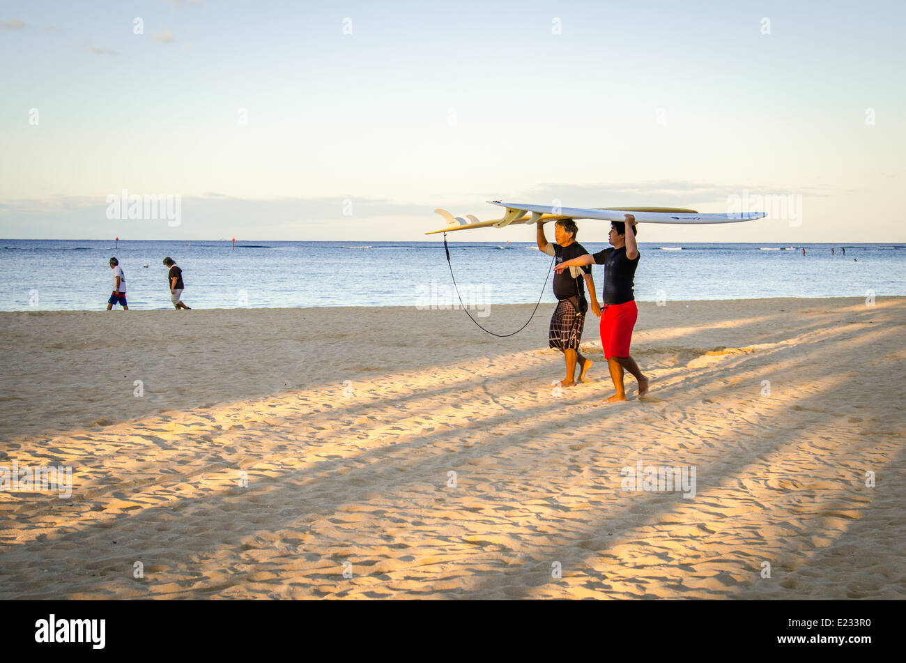 Leurs Surfers carrying surfboards le long de la plage de Waikiki à Hawaï Banque D'Images
