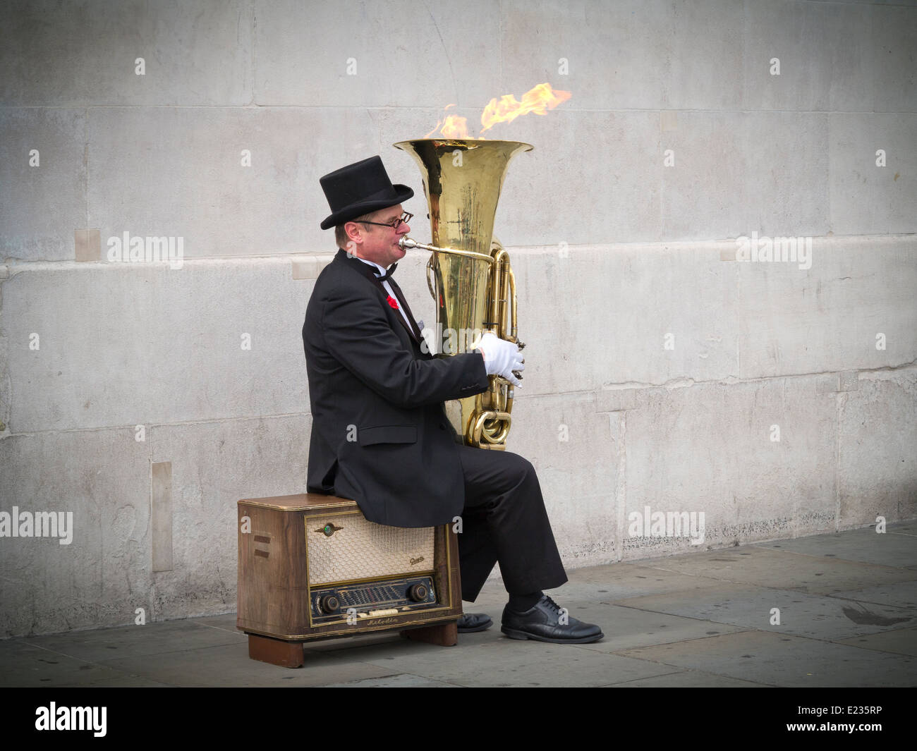 Musicien ambulant, Christopher Werkowicz jouant son flaming tuba assis sur une vieille radio contre un mur de pierre Londres Angleterre Banque D'Images