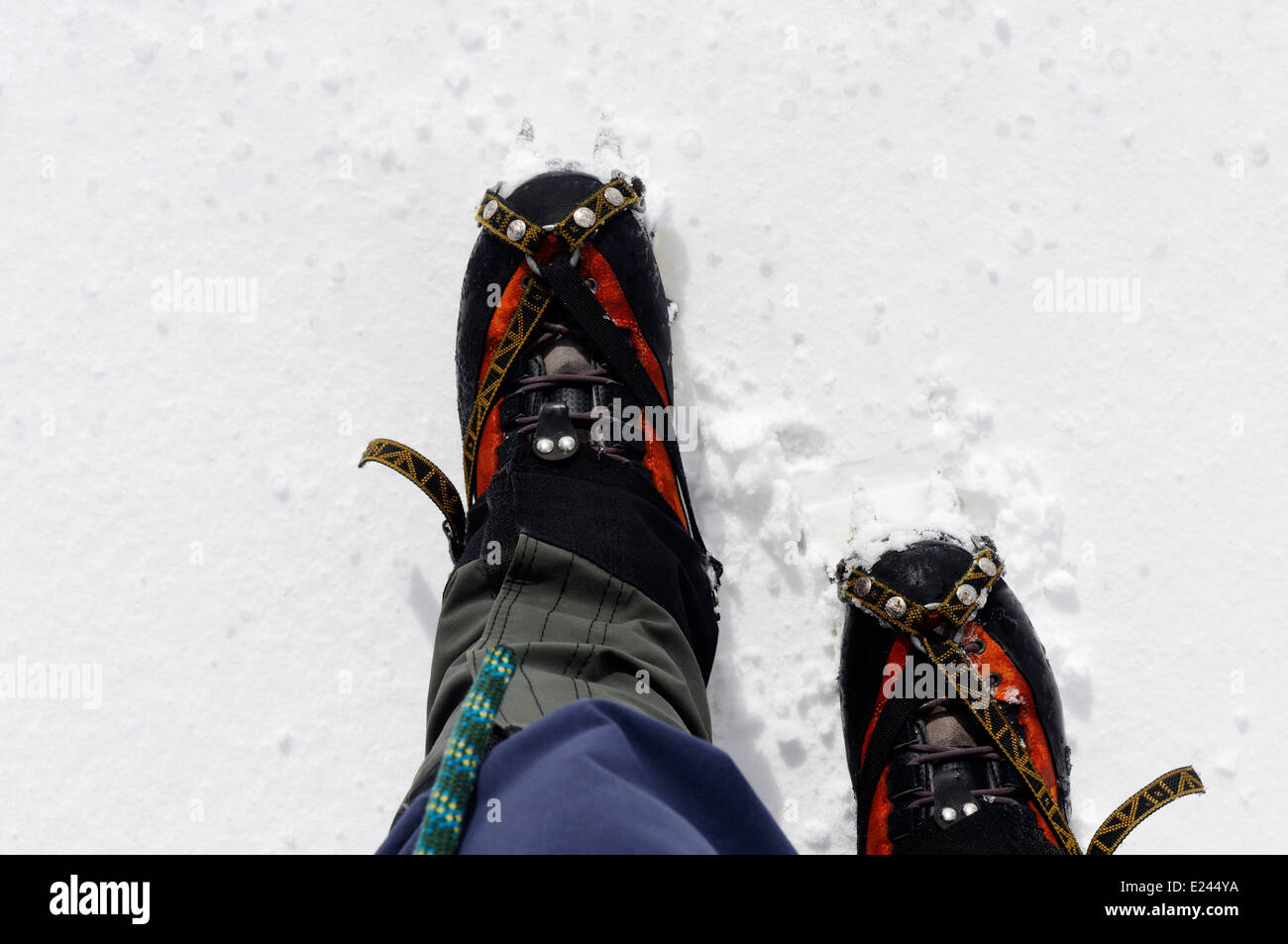 Les pieds de l'alpiniste dans la neige, avec des guêtres, corde et crampons visible Banque D'Images