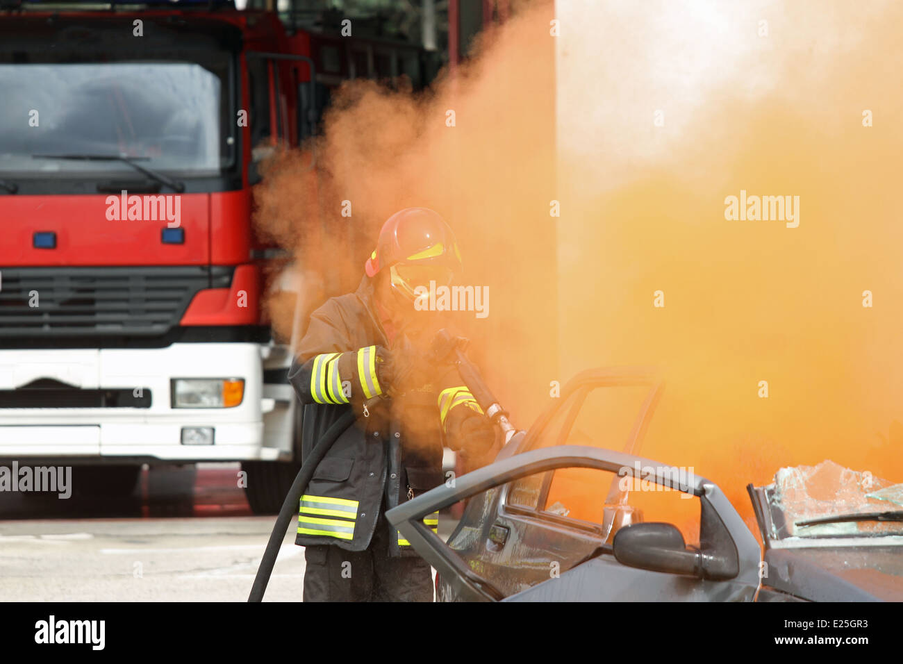 Pompier utilise un poteau incendie vers une voiture avec de la fumée Banque D'Images