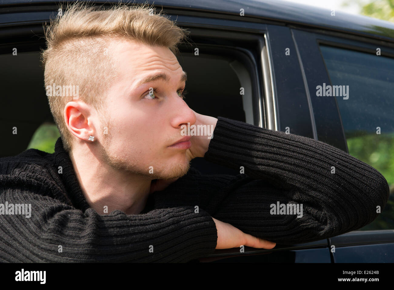 Beau jeune homme blond assis dans sa voiture, à out Banque D'Images
