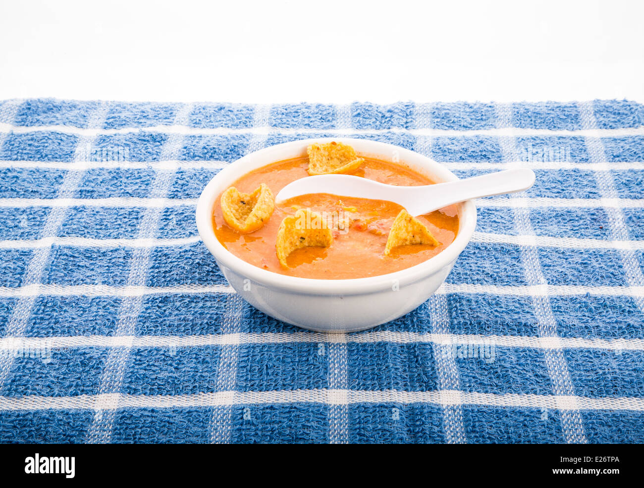 Un bol de soupe de tortillas chaudes et épicées sur une serviette à carreaux bleu Banque D'Images