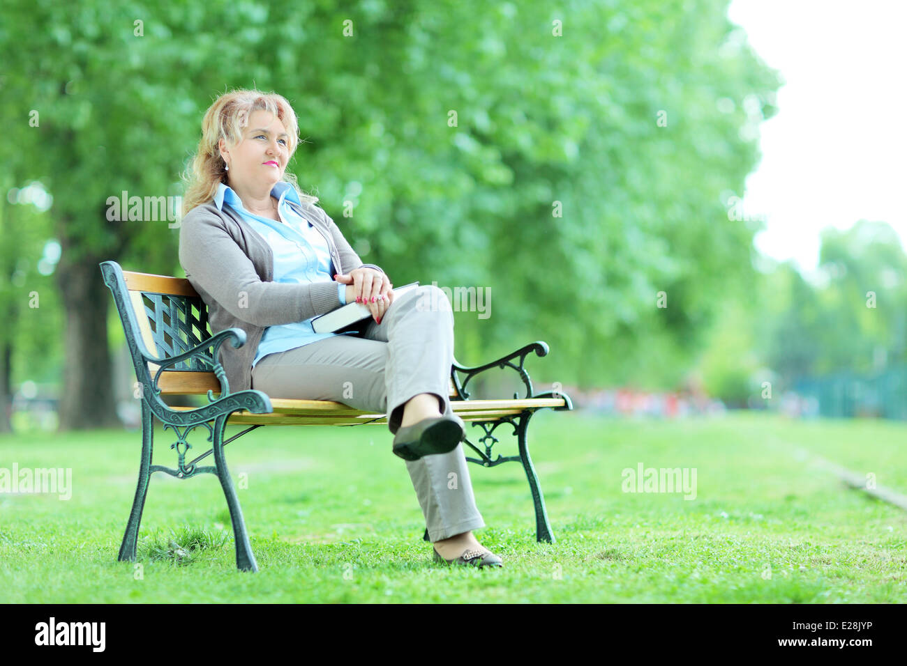 Dame mature se détendre dans un parc assis sur un banc Banque D'Images