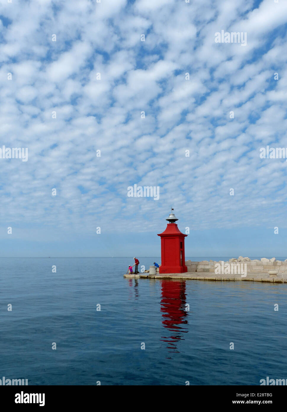 Seascape with a red post navigation de plaisance pour entrer dans le port de plaisance, ainsi qu'un petit groupe de personnes la pêche au large de la jetée Banque D'Images