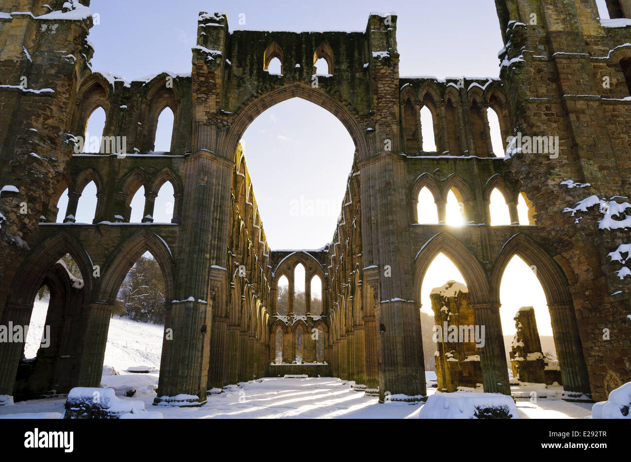 La lumière du soleil qui brillait à travers les fenêtres voûtées de l'abbaye cistercienne et dans la neige, l'abbaye de Rievaulx, North York Moors N.P., North Yorkshire, Angleterre, Janvier Banque D'Images