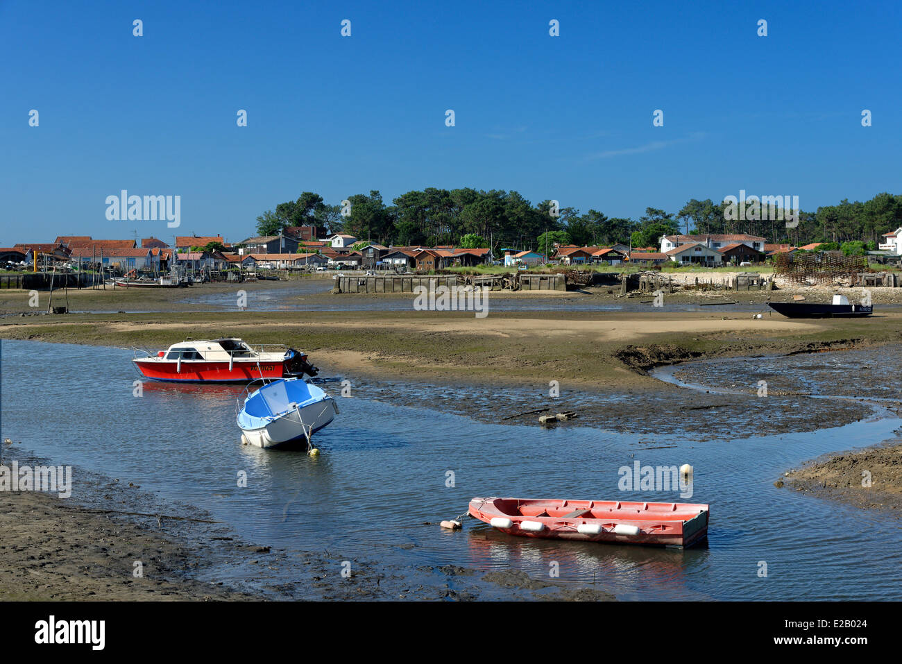 France, Gironde, Arcachon, Piraillan, bateaux dans un canal à marée basse avec village de pêcheurs dans l'arrière-plan Banque D'Images
