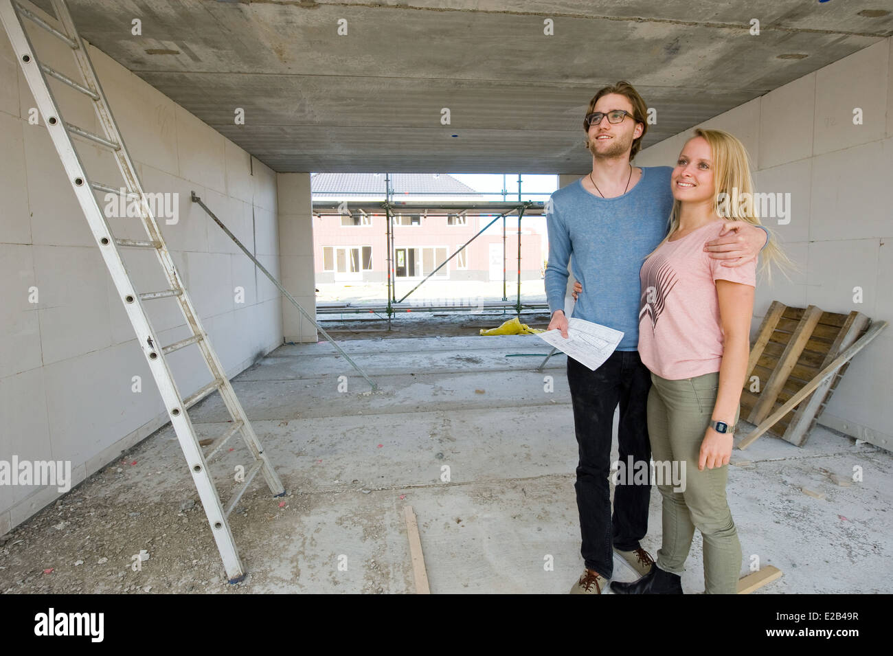 Jeune couple avec blueprint est à leur nouvelle maison heureusement comment se construit. Banque D'Images