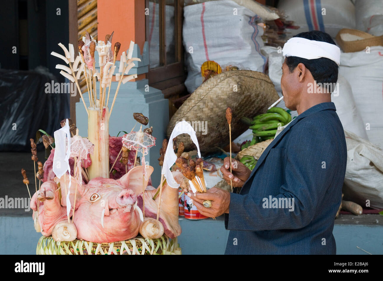 L'INDONÉSIE, Bali, près de Bedugul, Temple Ulun Danu Batur, cérémonie religieuse annuelle, l'homme de préparer une offrande, chef de pig Banque D'Images