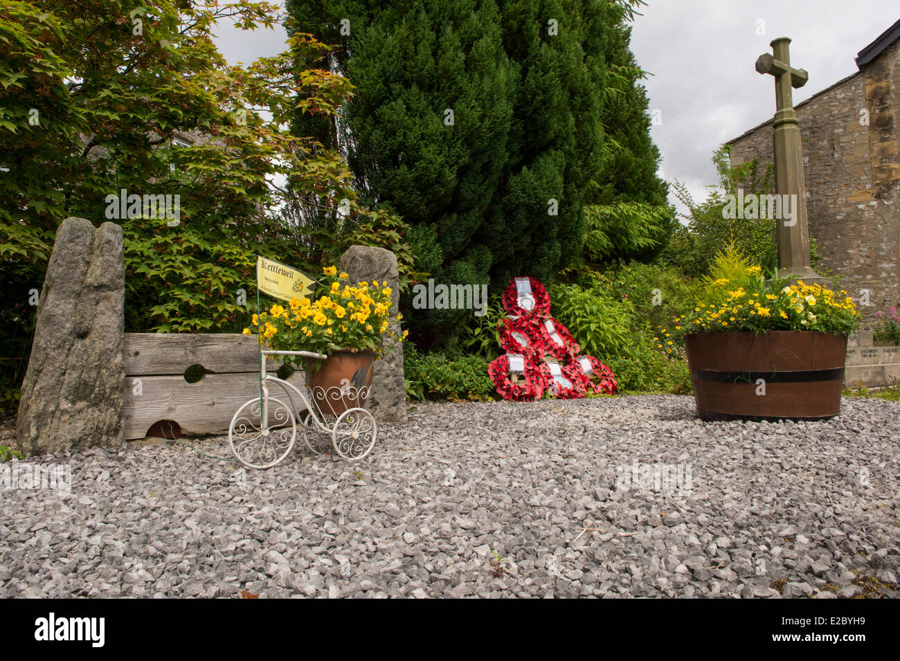 Petit quartier calme beau jardin avec stone War Memorial, pavot couronnes, fleurs en pots et stocks village - Kettlewell, Yorkshire, Angleterre, Royaume-Uni. Banque D'Images