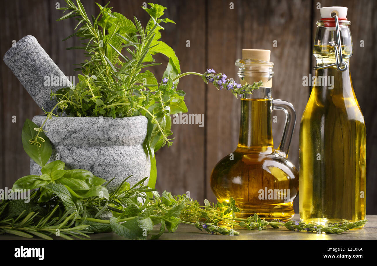 Les herbes et l'huile sur table en bois Banque D'Images