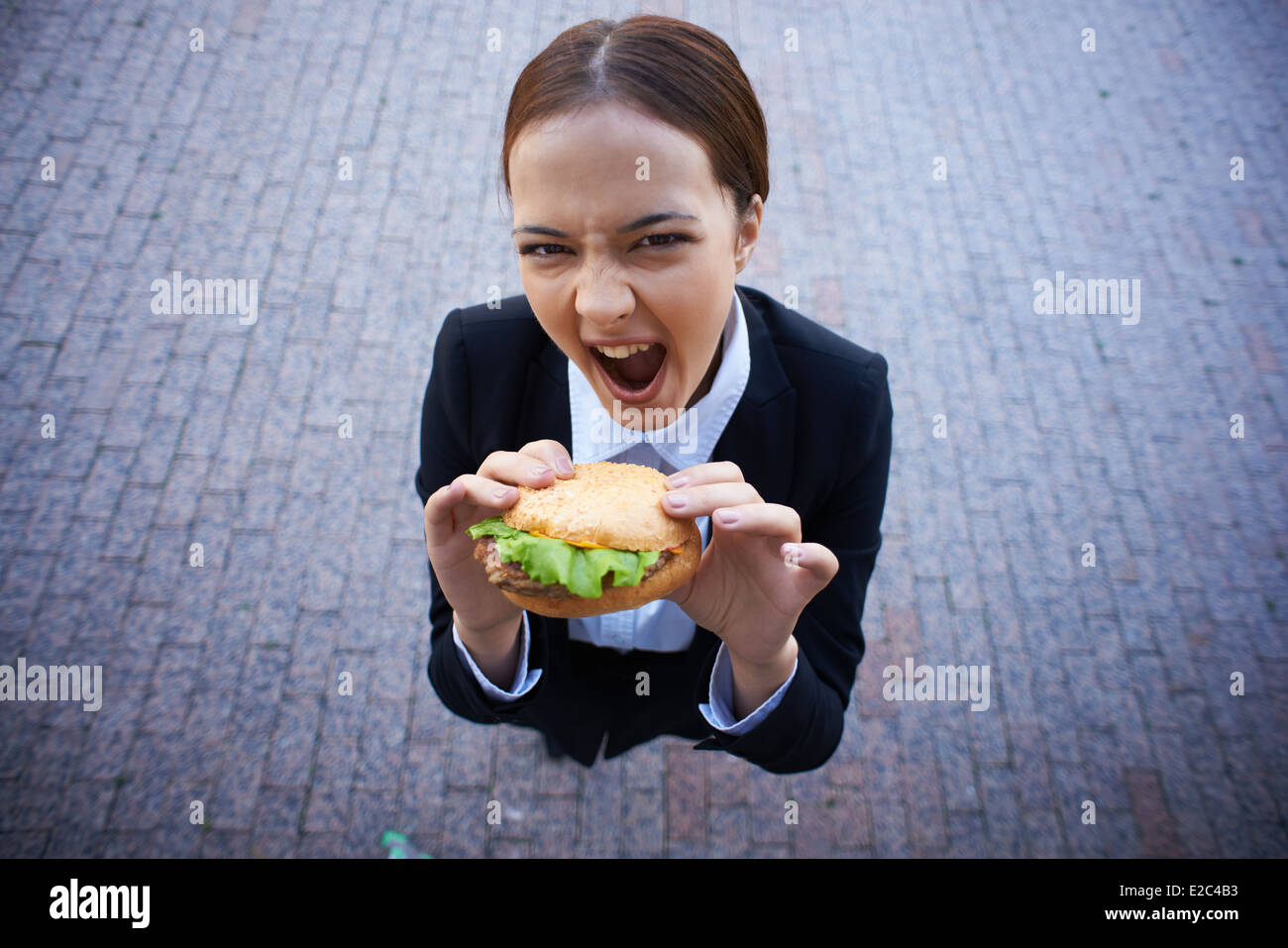 Image de très faim businesswoman with sandwich à la caméra à l'extérieur Banque D'Images