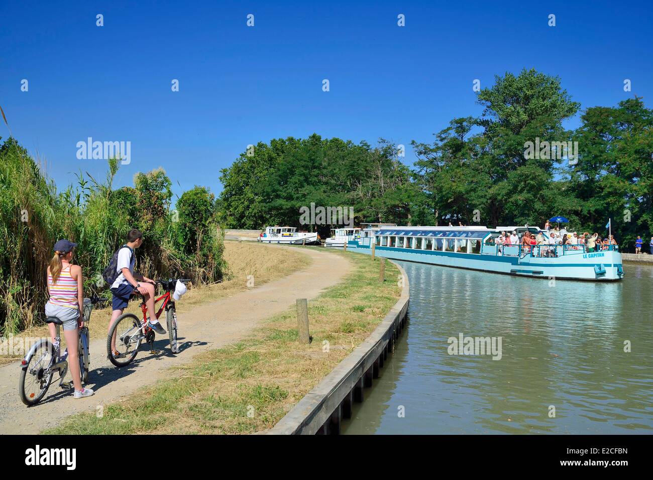 La France, l'Hérault, Béziers, Canal du Midi, classé au Patrimoine Mondial par l'UNESCO, les cyclistes en regardant une péniche à l'écluse Notre Dame Banque D'Images