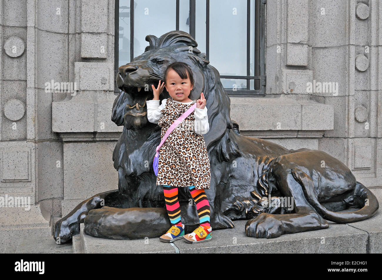 Une jeune fille chinoise qui pose devant un lion de bronze guard Shanghai Chine Banque D'Images
