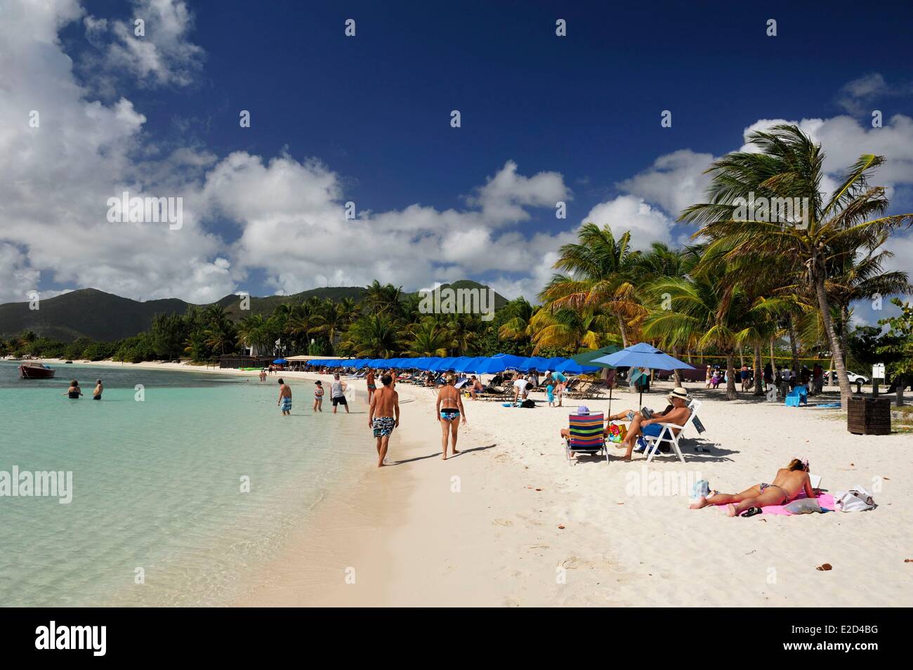 France Guadeloupe Saint Martin : Le Galion deux personnes marchant vers le bleu parasols alignés sur la plage aux eaux turquoises Banque D'Images