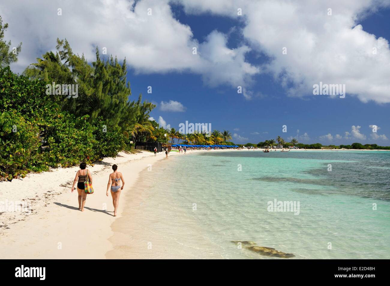 France Guadeloupe Saint Martin : Le Galion deux personnes marchant vers le bleu parasols alignés sur la plage aux eaux turquoises Banque D'Images